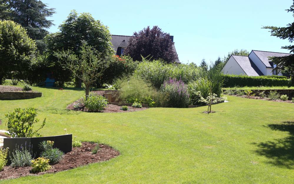 Jardin d'assainissement par phytoépuration avec bassins plantés de roseaux et végétaux filtrants intégrés au paysage
